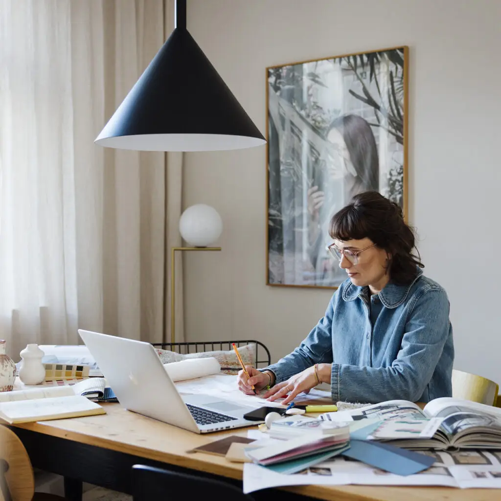 Stephanie Loy, Innenarchitektin München, sitzt arbeitend am Schreibtisch