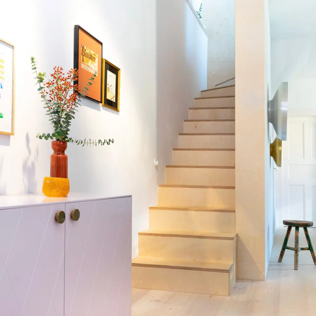 Moderne, offene Holztreppe in farbenfroh eingerichtetem Apartment, gestaltet von Stephanie Loy Interior Design